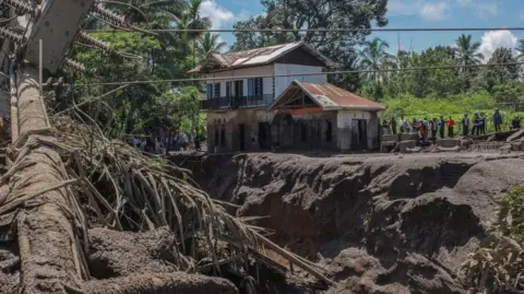 Villagers gather near a damaged house in Tanah Datar