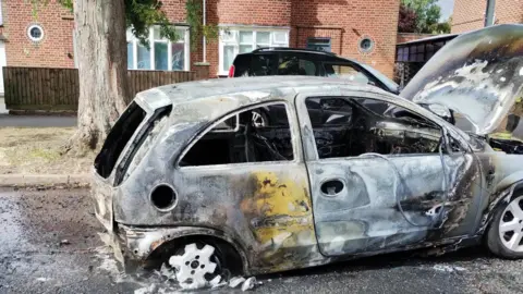 Leicestershire Police A destroyed white Vauxhall Corsa on the road 