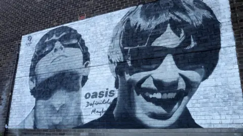 Reuters An Oasis mural on a brick wall featuring black-and-white portrayals of Noel and Liam Gallagher