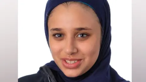 A headshot photo of Sara El-Khawas wearing a hijab and looking at the camera smiling against a white background.