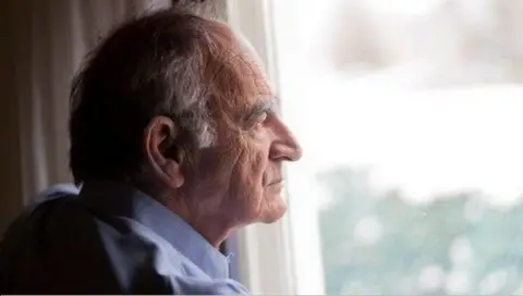 Thinkstock An elderly man wearing a blue shirt, looking our a window