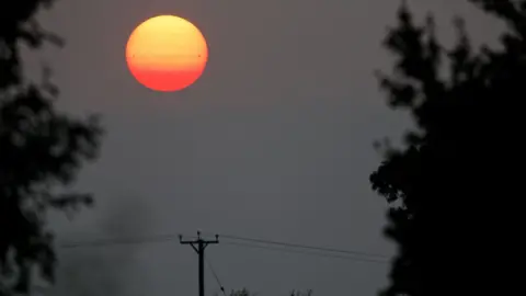 Jamie Cooper Setting sun seen above power lines in Northamptonshire