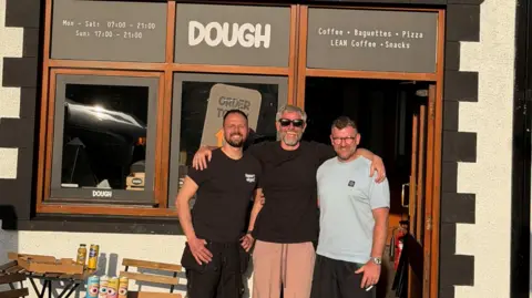 Jamie Watkins Three men stood outside a pizza shop 