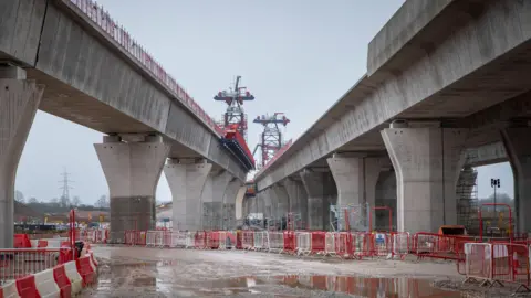 HS2 Ltd Two huge concrete viaducts can be seen parallel to each other, with puddles on the ground beneath them.