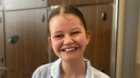 Claire Hamilton/BBC Rose has her hair tied back and wears a care worker uniform