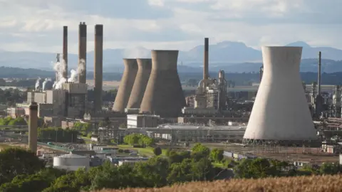 Cooling towers and industrial facilities with rolling hills in the background 