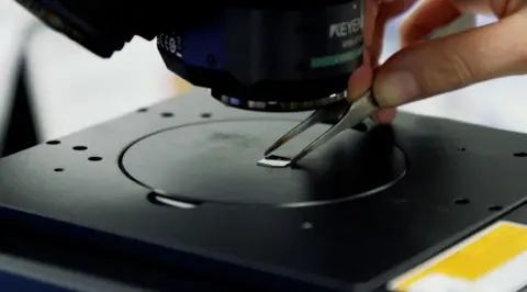 Loughborough University The chip bearing the image of "the world’s smallest violin" positioned under a microscope