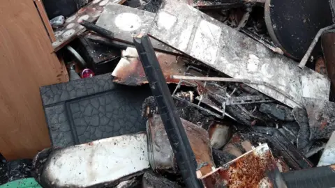 Derek Smith Burnt rubble, heaped up in a large pile.