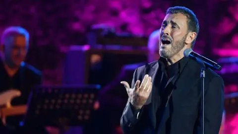  Fethi Belaid / AFP An image of Iraqi singer Kadim al-Sahir performing at at the International Festival of Carthage at the Carthage Roman Theatre on the outskirts of Tunis, the capital of Tunisia on 3 August 2024.