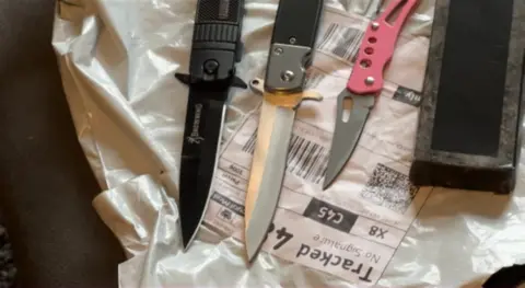 Three knives placed on top of plastic packaging with an address label