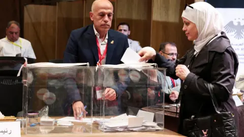 Reuters A female member of an electoral college votes for candidates for the new Syrian People's Assembly, in Aleppo, Syria (5 October 2025)