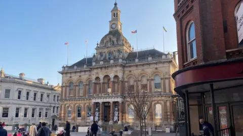 Exterior of Ipswich Town Hall on the Cornhill. An ornate sandstone building, with a dome and clock tower on top