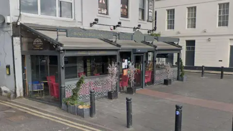 Google Streetview of the Wafi Lounge, it is a gray building with a glass conservatory-style section wrapping around the building.