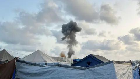 Smoke rises above tents sheltering displaced Palestinians, in Khan Younis, southern Gaza