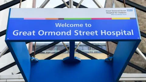 EPA/PETE MACLAINE View looking up towards a glass roof with a suspended blue sign saying "Welcome to Great Ormond Street Hospital".