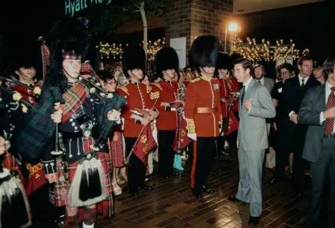 Getty Images The prince was greeted by actors during a visit to a department store in Los Angeles in 1977. The encounter appears to have elicited laughter from both the royal and from the men playing the King's Guard.