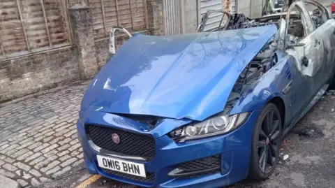 Met Police A blue Jaguar that has been partially burnt out.