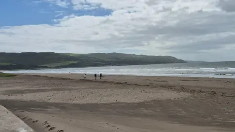 A beach, with only a few people on it.