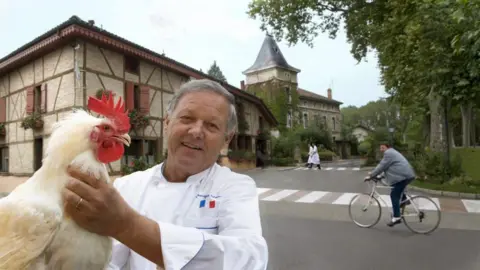 Georges Blanc pictured with a rooster outside his eponymous restaurant in 2011