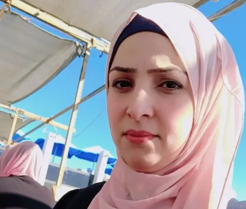 Islam Headshot of a woman wearing a pale pink headscarf and makeup.