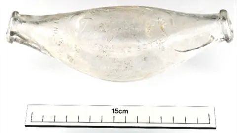 ODAIT A glass hygienic baby feeder. It is a round cylinder shape with openings at both ends.