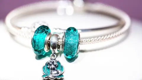Getty Images A Pandora charm bracelet with bright turquoise stones and a silver band.
