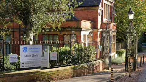Google Maps A brick building with black iron gates surrounding it with a silver sign for St Andrew's Healthcare on it.