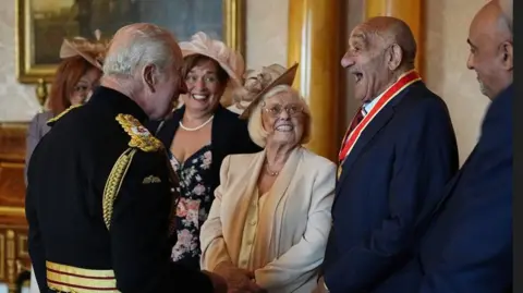 King Charles, Sir Billy Boston and the rugby league star's family members share a joke at his knighthood investiture.