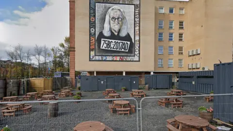 Google Images The building site with benches and portable toilets set up.