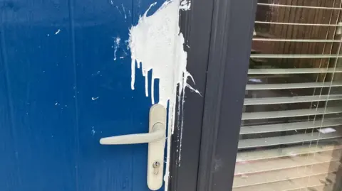 A white splash of paint is visible on a blue door near the door handle. 
