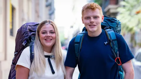 BBC/Studio Lambert Brother and sister Harrison and Katie with their backpacks on, smiling at the camera