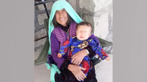 Supplied Pervin's grandmother is wearing a green headscarf and carrying a baby