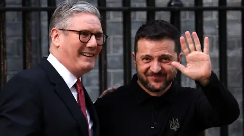 Standing outside of No10 Downing Street, Prime Minister Sir Keir Starmer (on the left) shakes hands with Ukrainian President Volodomyr Zelensky, who waves