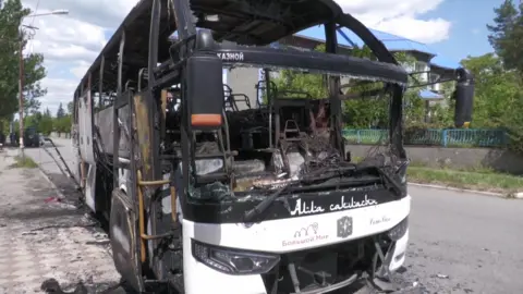Reuters A frontal view of a destroyed civilian bus in the Russian -controlled region of Donetsk. The inside of the white bus is completely burnt out and the windows have been shattered. 