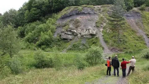 Colin Prosser Four people stand at the foot of rocks which form part of Saltwells local nature reserve