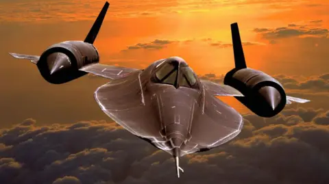 Getty Images A 1960s US Air Force Lockheed SR-71 Blackbird military reconnaissance jet Aircraft in the air. It has a flat body, a bit like a manta ray, with two fat engines on its flat wings. There is an orange sunset behind it and beneath it a huge stack of clouds. 