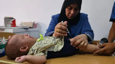 Getty Images A medical team from the Palestinian Red Crescent administer polio vaccine to children as part of routine campaign at Al-Amal Hospital in southern Gaza's Khan Younis city on August 22, 2024. 