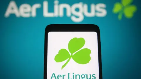 Getty Images UKRAINA - 23/01/2022: Dalam ilustrasi foto ini, logo Aer Lingus terlihat di layar ponsel pintar dan komputer. (Ilustrasi Foto oleh Pavlo Gonchar/SOPA Images/LightRocket via Getty Images)