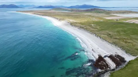 Eilidh Carr An aerial view of West Beach at Bays of Harris in the Western Isles. There is a long strip of white sand and turquoise sea.