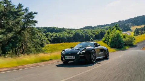 A scenic countryside view with a cool, black sports car speeding through