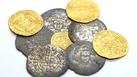 A collection of coins from the 15th Century in silver and gold with faces on some of them