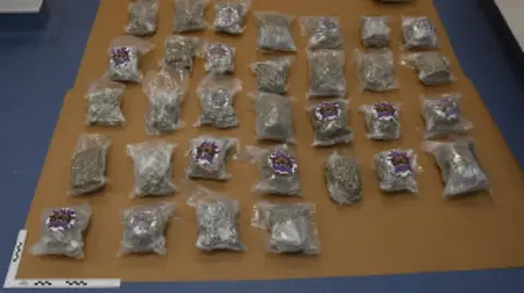 Sealed bags of cannabis laid out on a beige and blue floor.