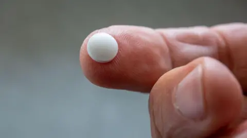 Close-up of white pill on a finger-tip