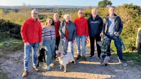 Office of Vikki Slade MP Vikki Slade poses with five men, a woman and three dogs on Upton Heath