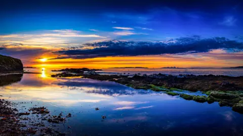 Robert Westerman A golden sunset over dark blue water.
