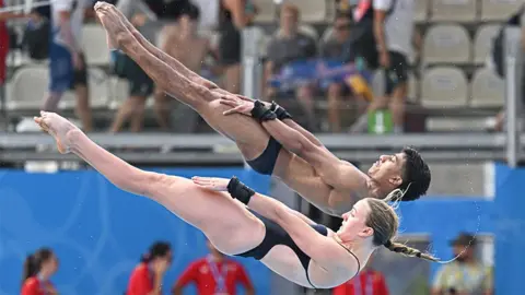 Getty Images Kyle Kothari and Lois Toulson in a synchronised diving pose, compete during the Diving Mixed Synchronised Platform final event