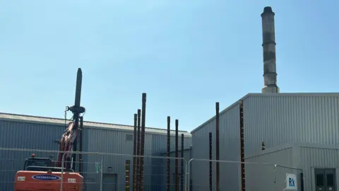 Grey incinerator building with work beside it at Longue Hougue in Guernsey. 