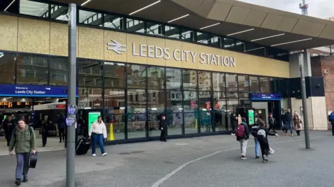 Leeds City Station: a glass fronted building with a large gold and white sign.