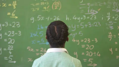 Getty Images A girl in uniform KwaZulu Natal looking a maths equations on a board at school, South Africa