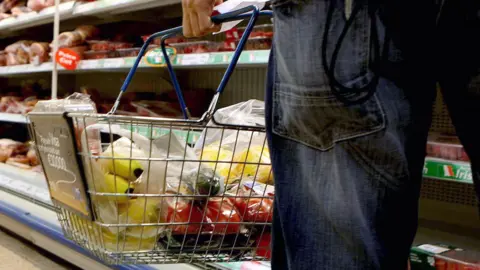 A person holding a shopping basket in a supermarket.